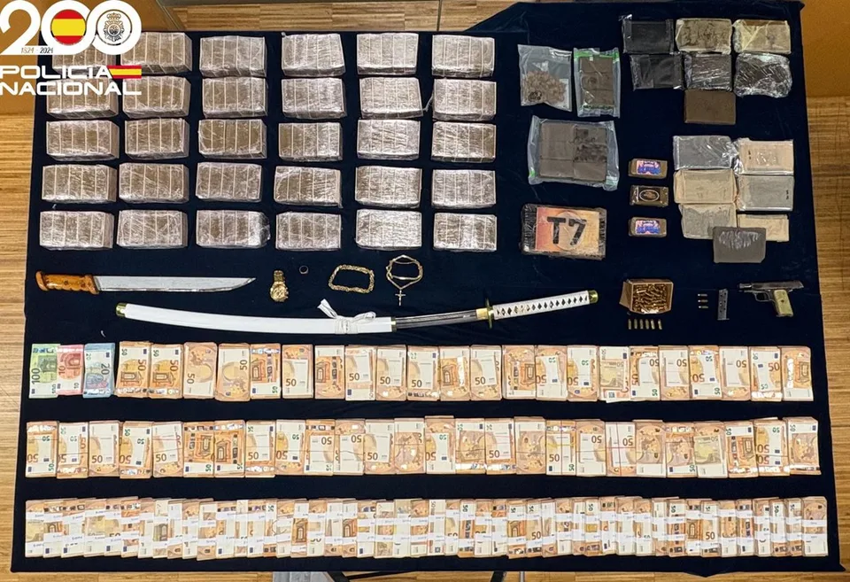 Billetes de euro, paquetes intervenidos y varias armas y objetos dispuestos sobre una mesa policial.